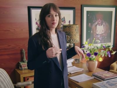 Dakota Johnson is wearing a blue coat as she is showing her house in the picture.